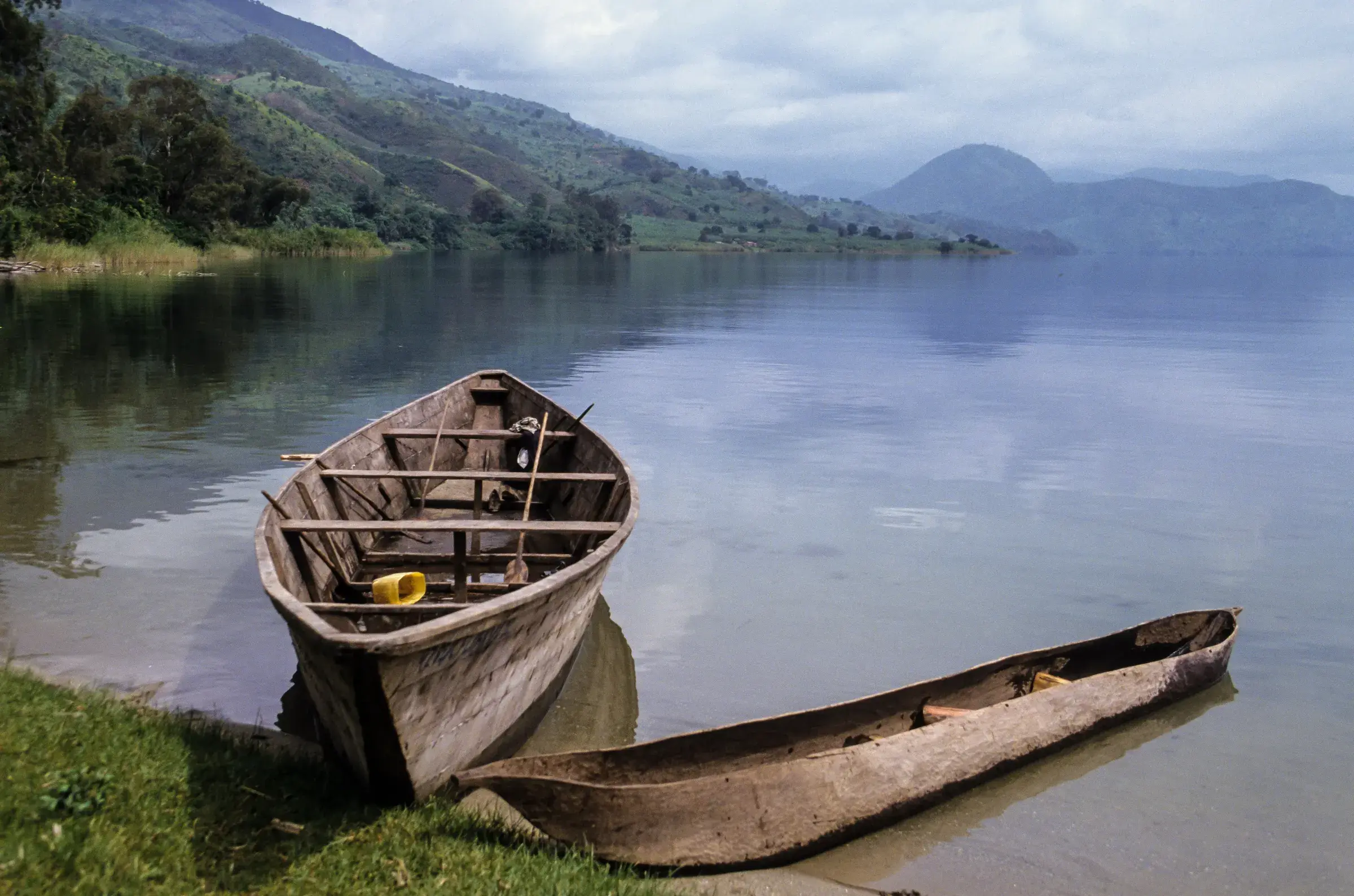 A fishing boat rests on Lake Kivu, the hills soft in the morning haze.