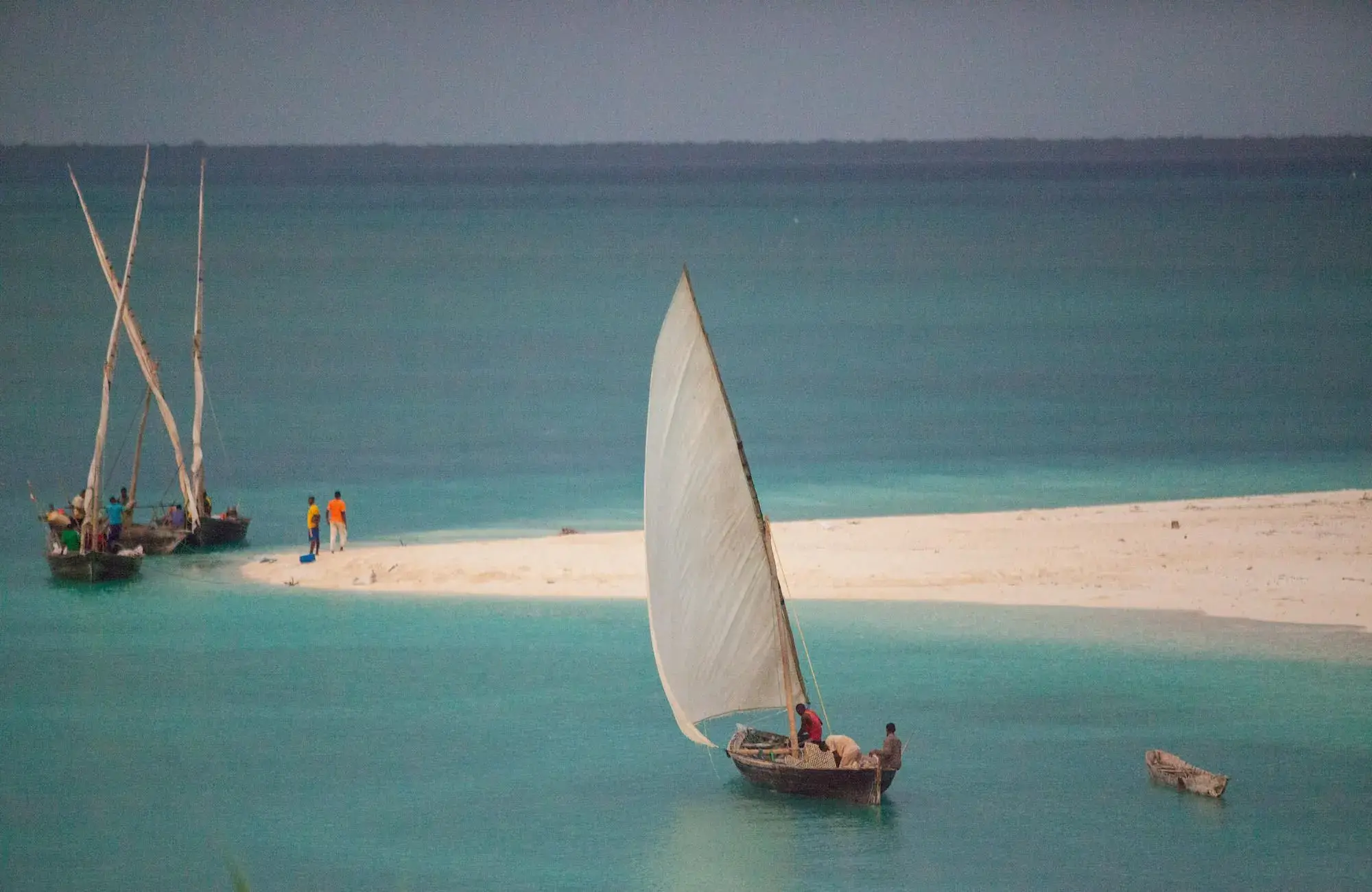 A dhow sail fills off Kendwa, the water running clear to the horizon.