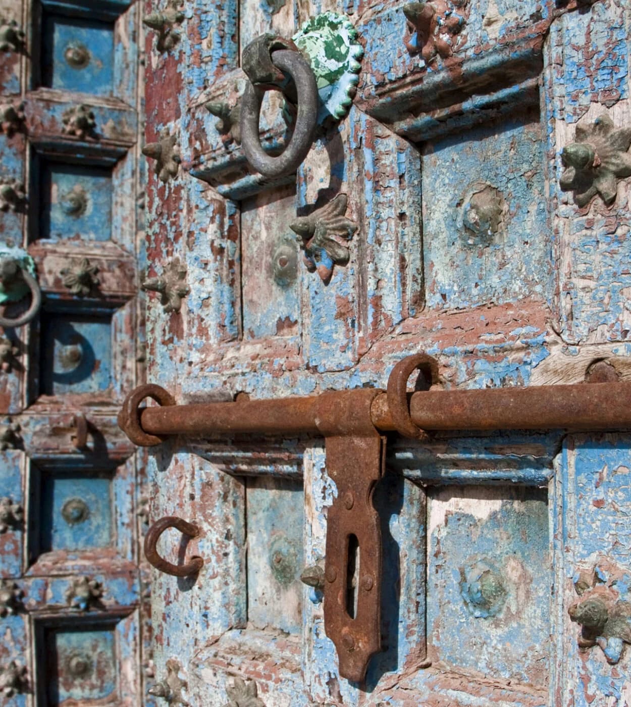 Weathered blue studded door with rusty iron latch, close