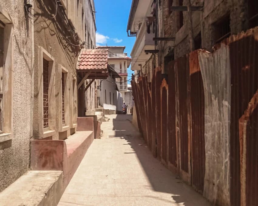 Narrow sunlit Stone Town lane with weathered walls