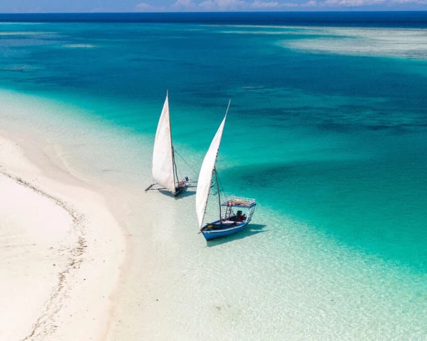 Aerial of two dhows on a white sandbank in turquoise water