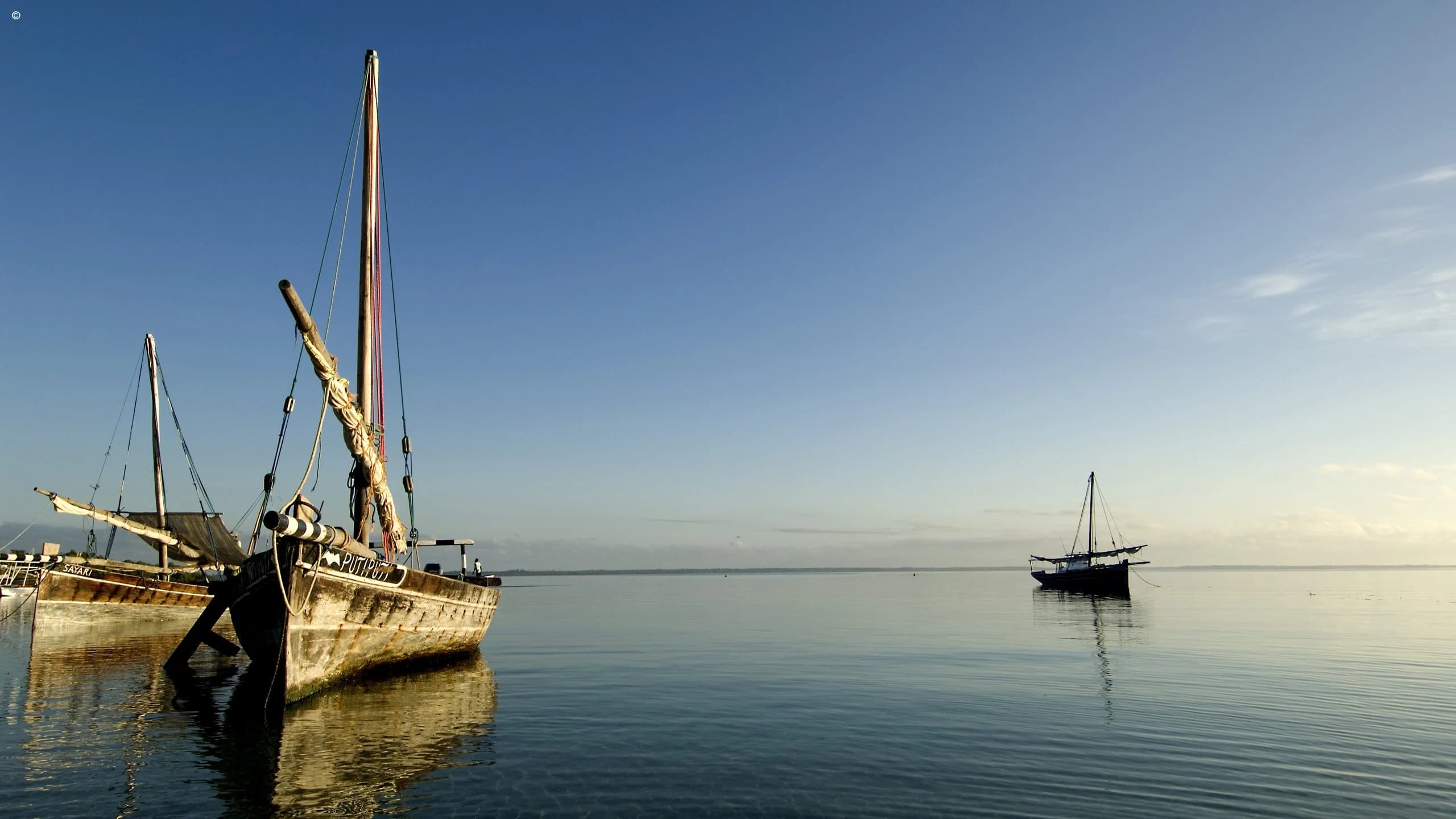 Dhows on calm blue grey water at dusk