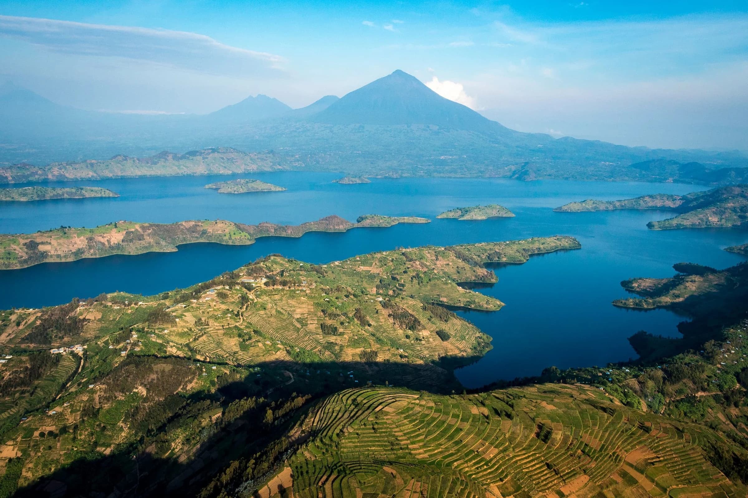 Aerial of blue lakes and Virunga volcanoes with terraced hills
