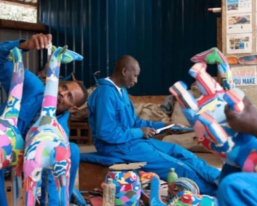 Craftsmen painting colourful flip flop giraffe sculptures in a workshop
