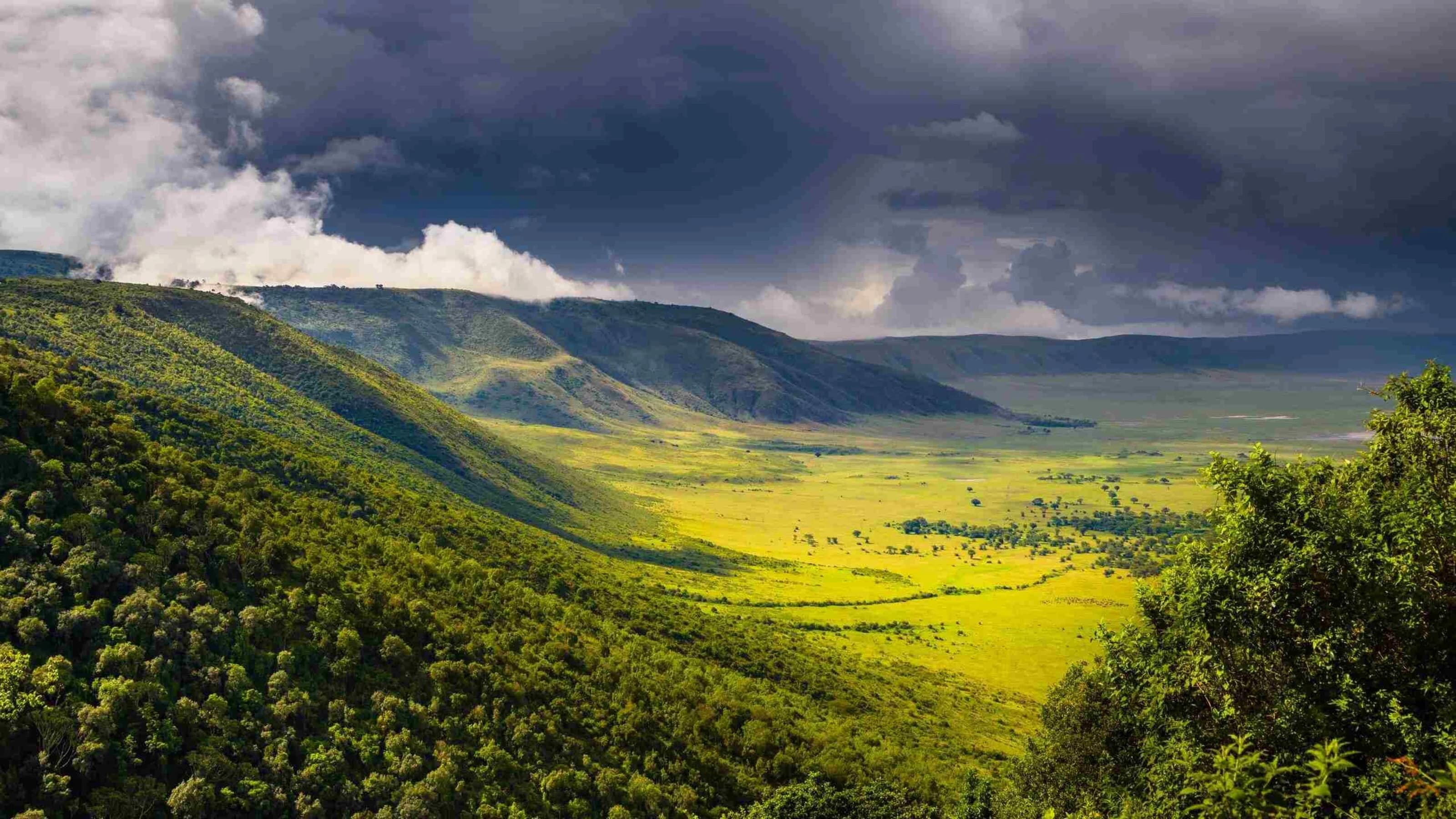 Storm clouds over the steep green walls and yellow floor of the crater
