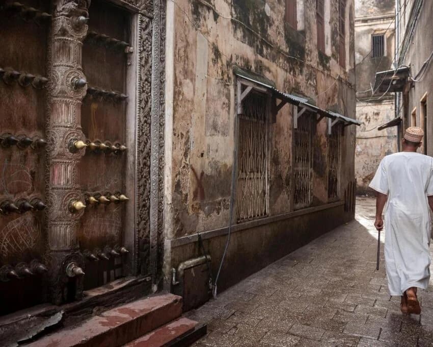 Carved wooden door in a Stone Town lane with a man in white