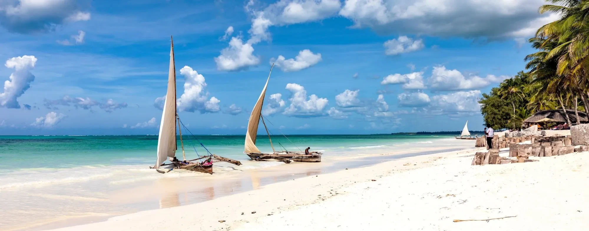 Dhows rest on the sand at Matemwe, the reef pale beyond the shallows.