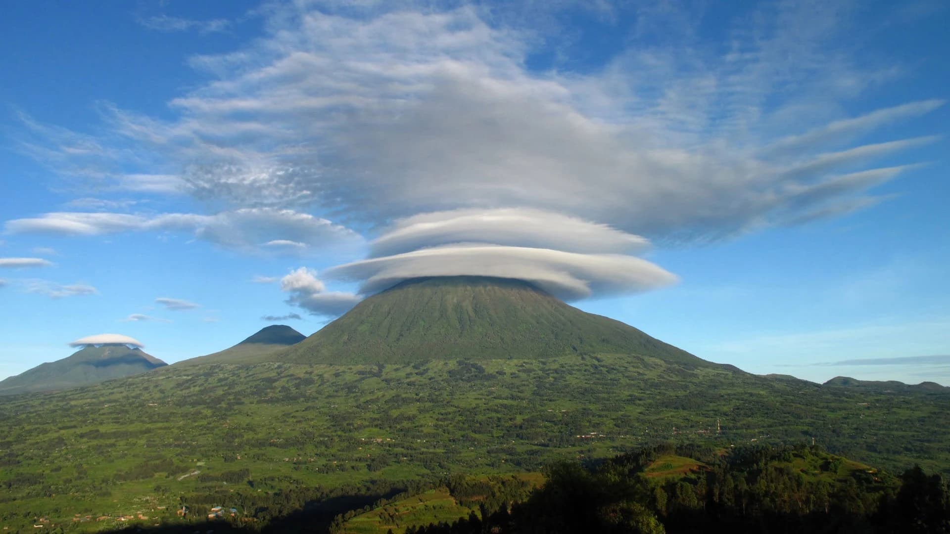 Lens shaped cloud cap over a Virunga volcano under blue sky
