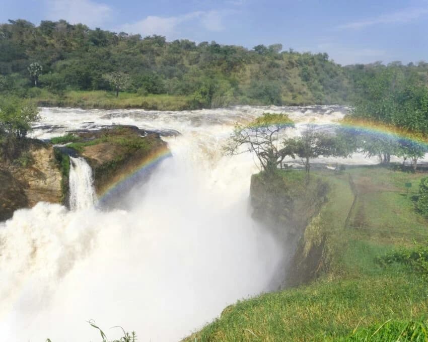 Wide waterfall with white spray and a rainbow across the gorge