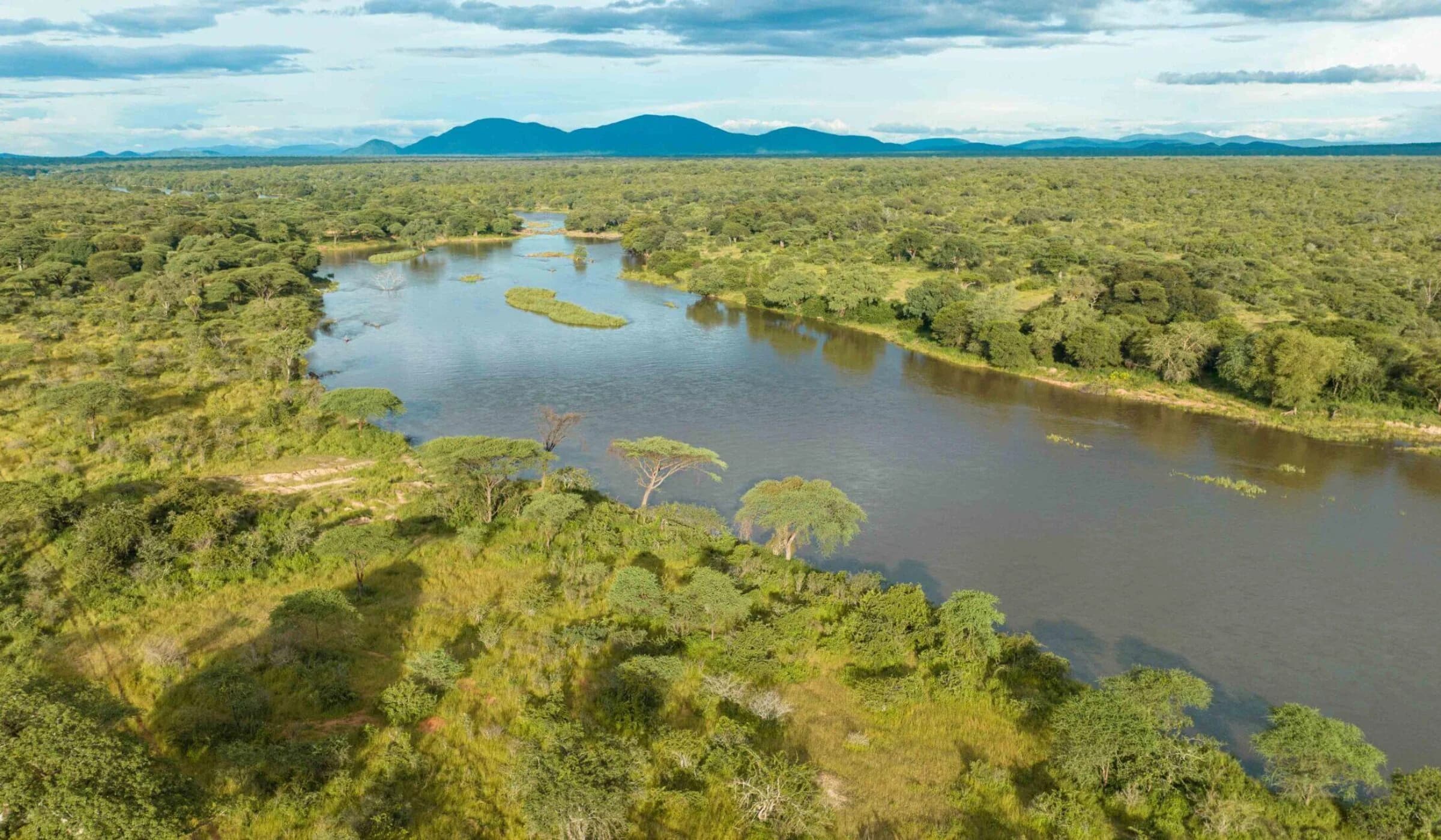 Aerial of a wide river winding through green woodland