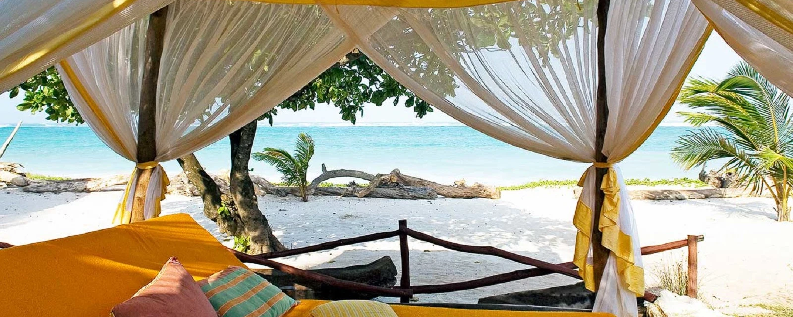 A canopied daybed looking out over a white beach on Kenya's coast