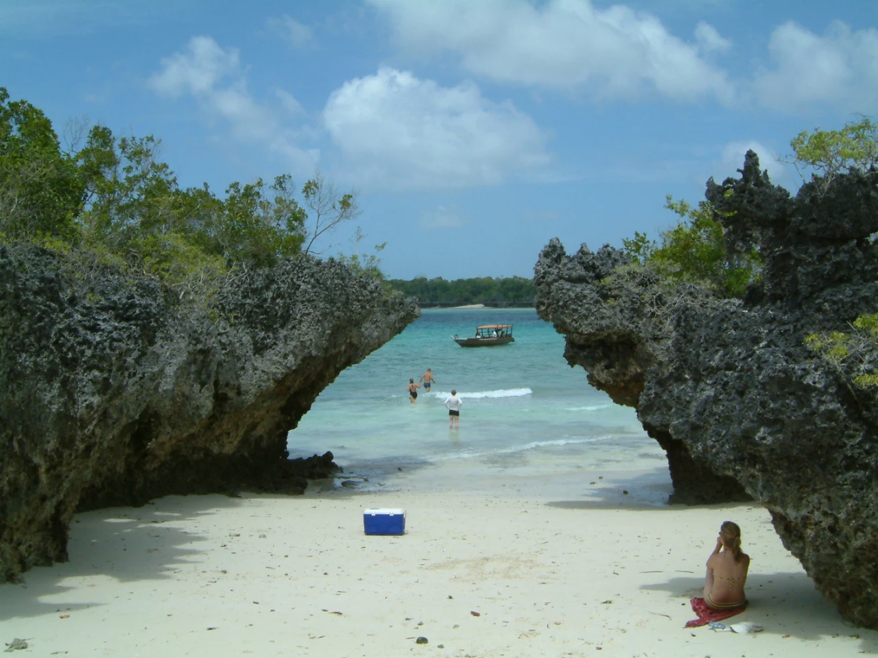 A dive boat moored in clear water between coral rock outcrops near Chake Chake