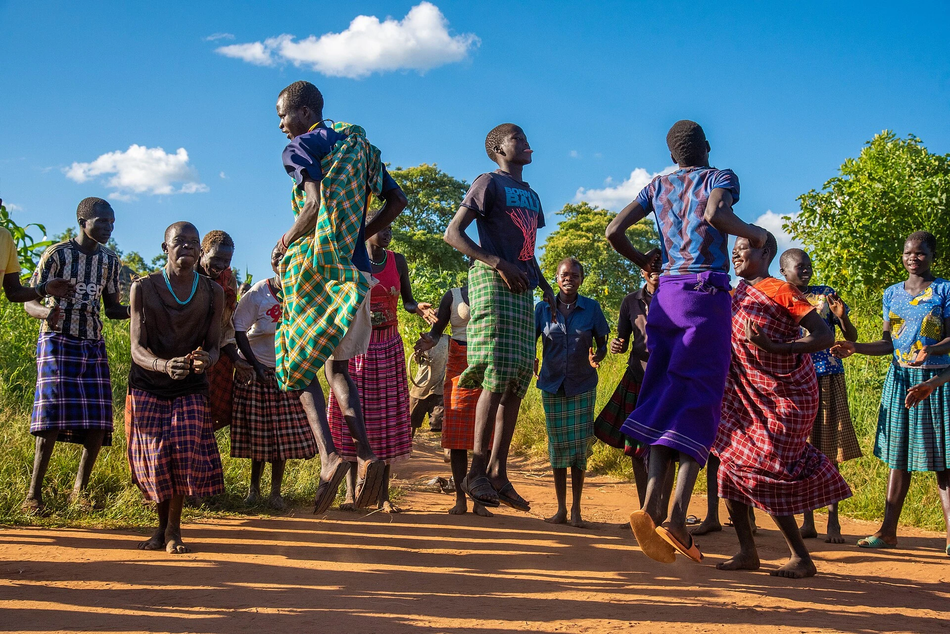 Karamojong men and women jumping and singing in a traditional welcome dance