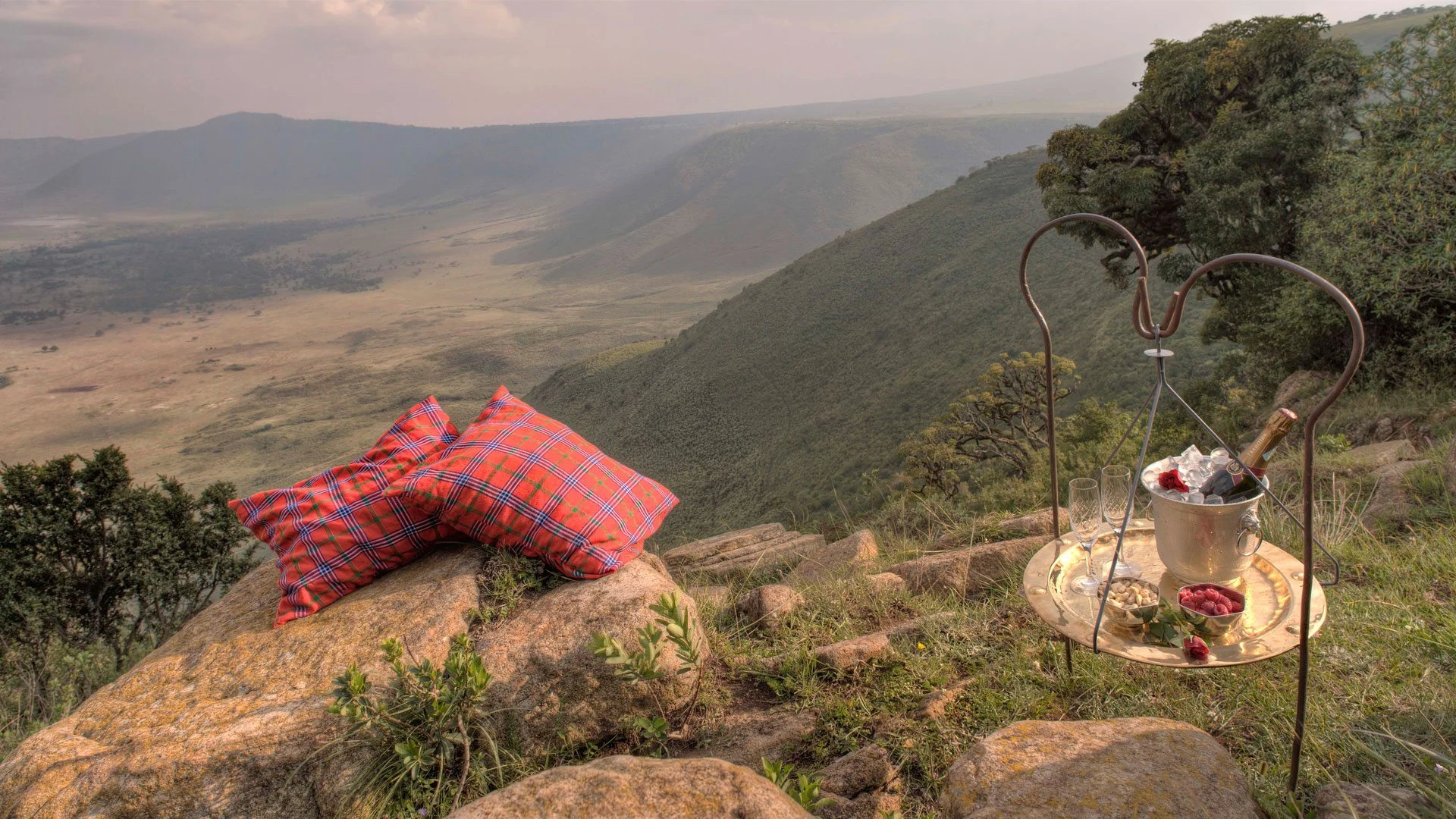 Cushions and drinks set on a rock on the crater rim at sunset