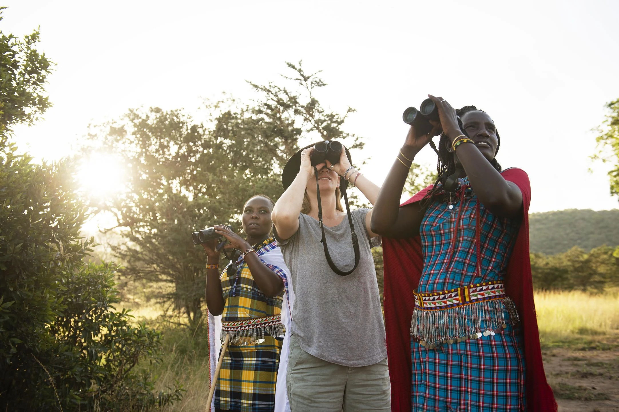 Guests with binoculars beside Maasai guides in Mara North
