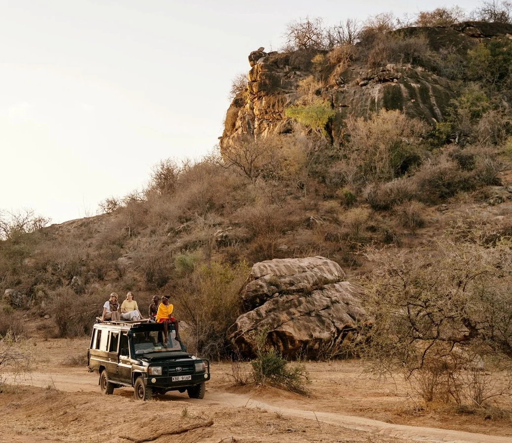 Safari vehicle below rocky hill