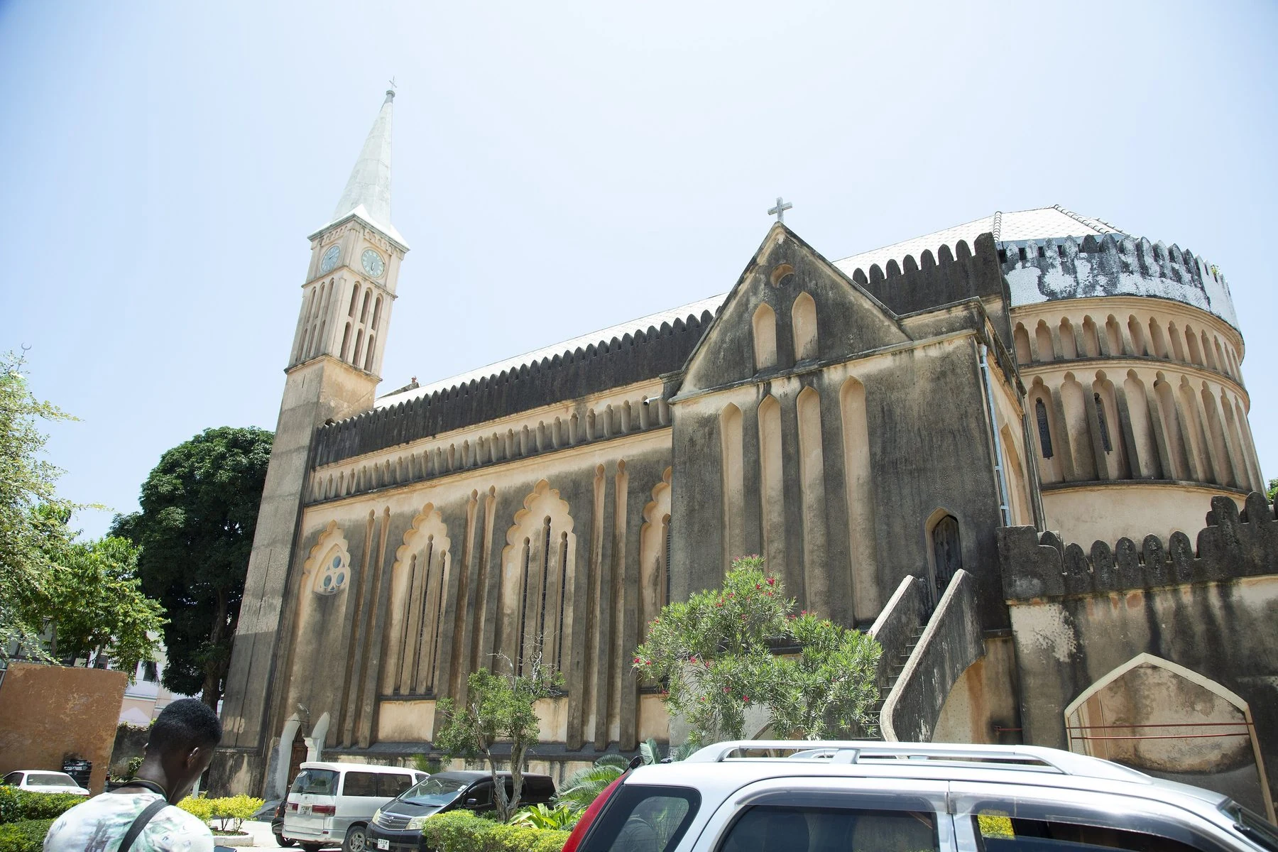 Stone cathedral with a tall spire above street traffic