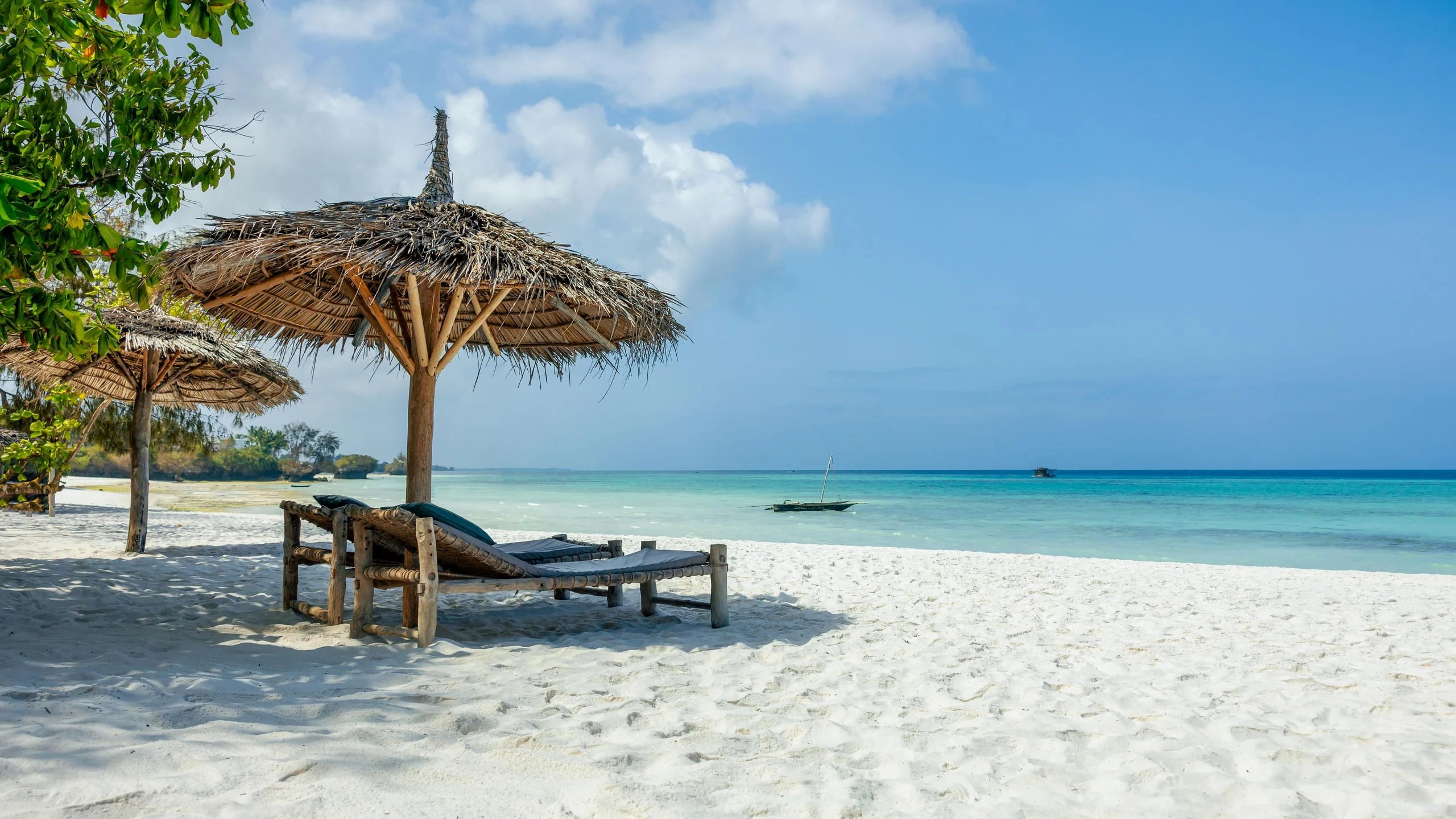 Sun loungers beneath parasols on a pale sandy beach