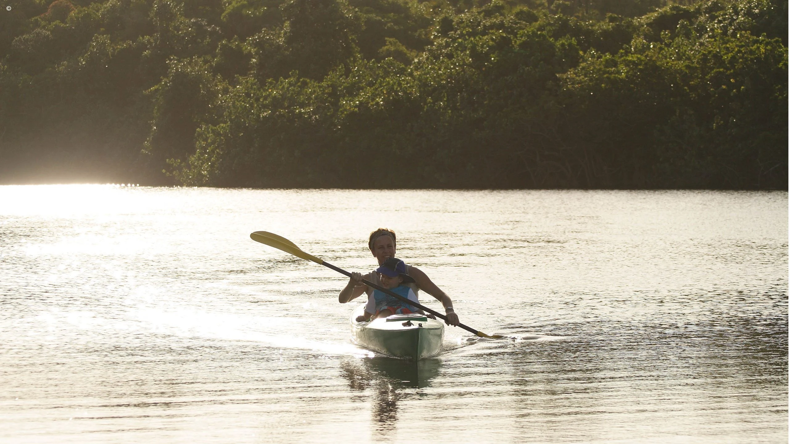 A kayaker paddling on bright, still water
