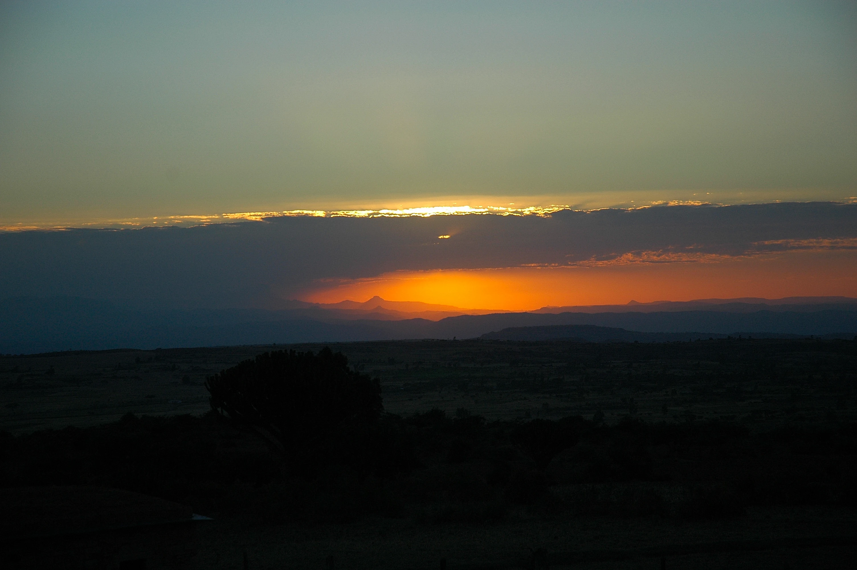 An orange sunset glows beneath cloud over the plains below Gheralta Lodge.