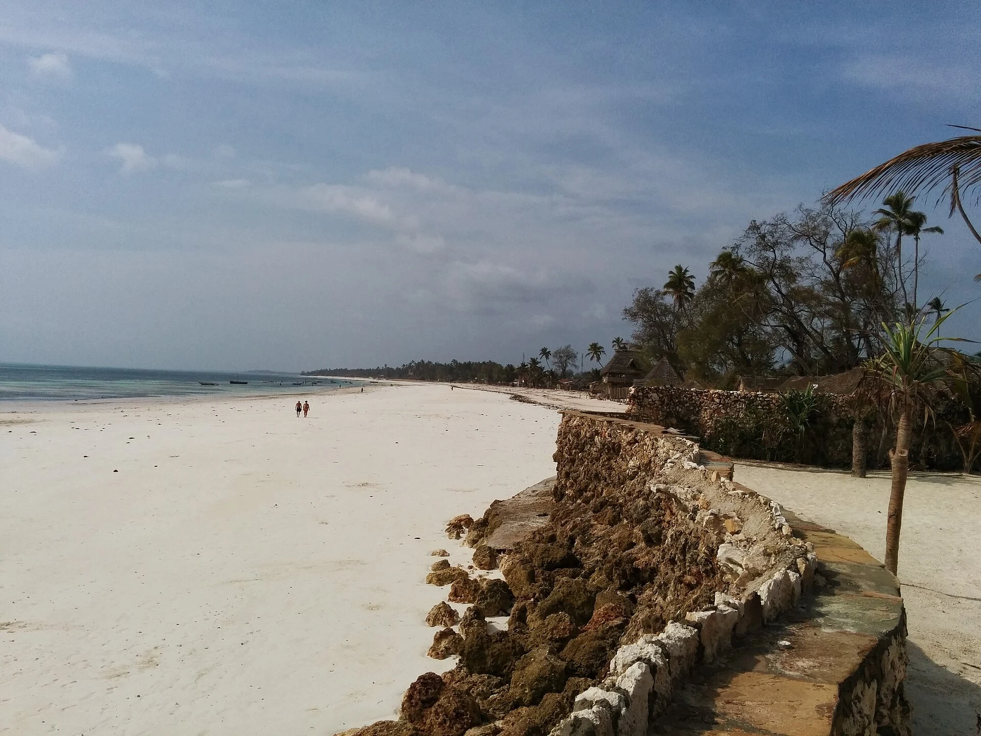 The wide white beach and coral-rock sea wall of Uroa Bay