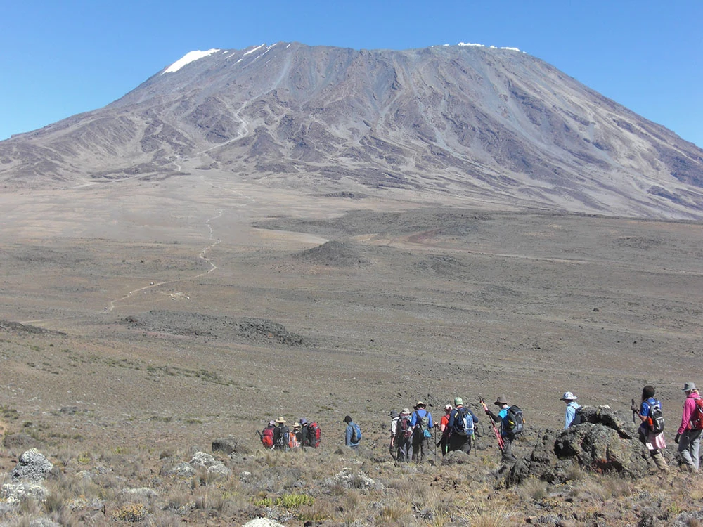 Trekkers crossing high moorland below the summit of Kilimanjaro