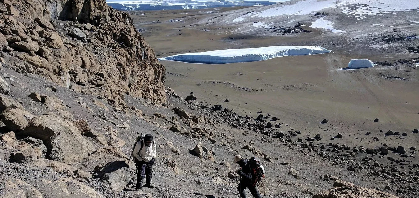Two hikers on a rocky slope below Kilimanjaro snowfields