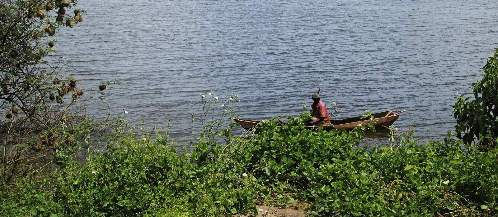 A fisherman paddling a wooden canoe on Lake Mburo