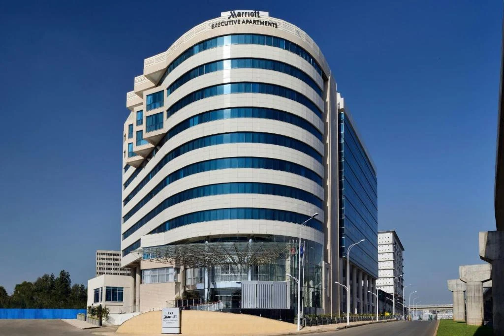 a tall glass building with a sign in front of it