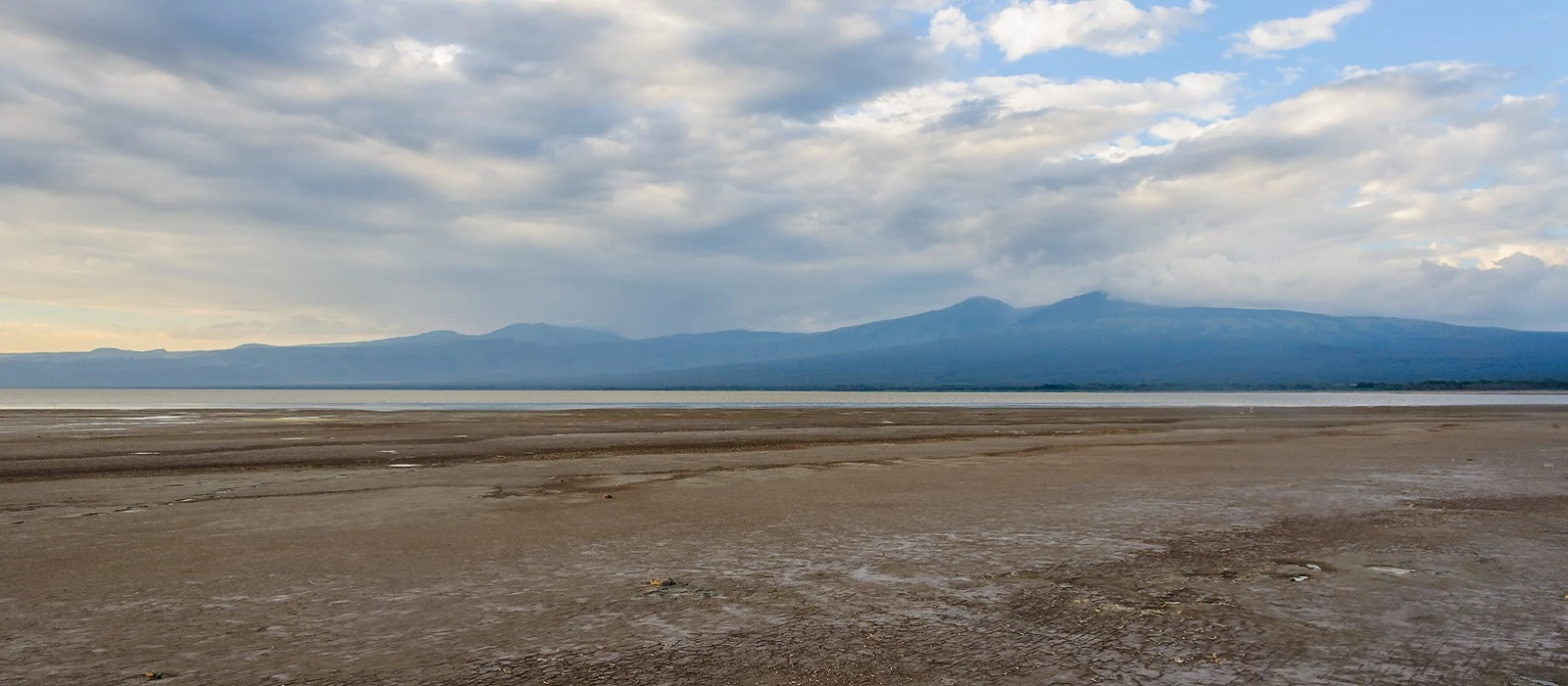 Wide shore flats of Lake Eyasi under a cloudy sky with distant hills