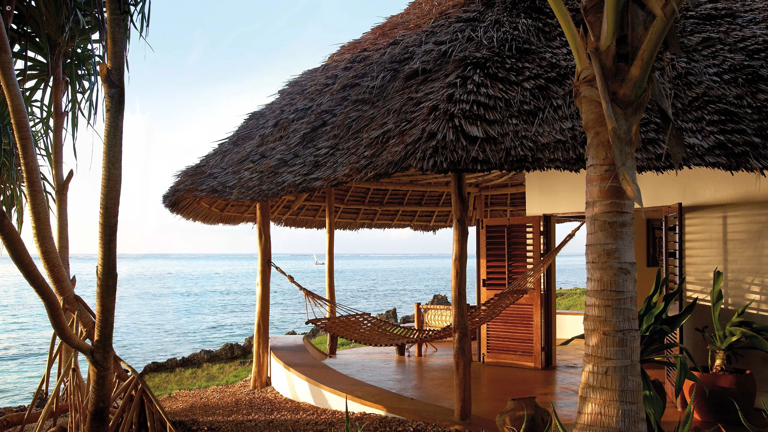Thatched sea view pavilion with hammock beside a palm at Matemwe Lodge