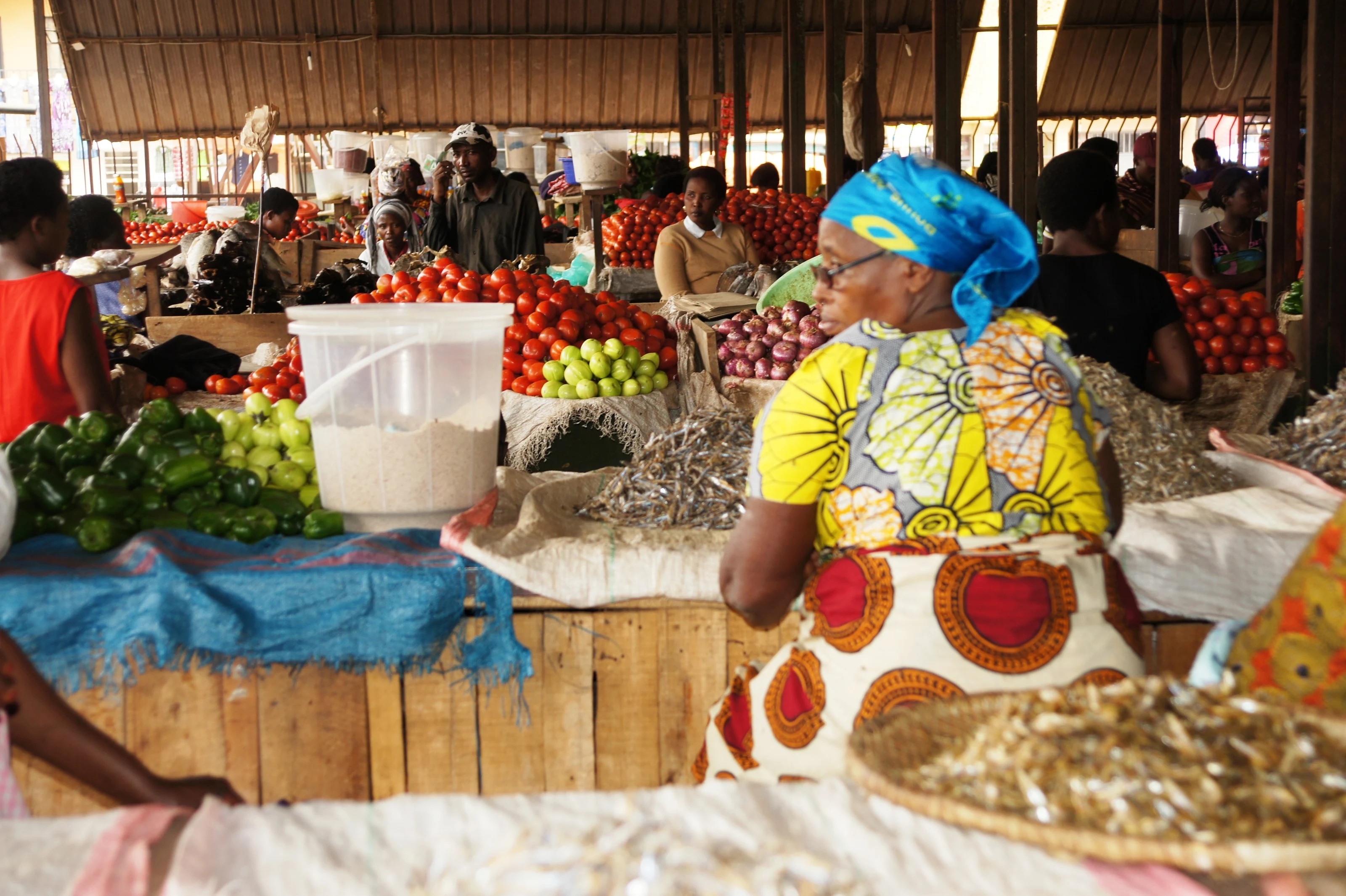 A trader in a colourful headscarf at her produce stall in a Kigali market