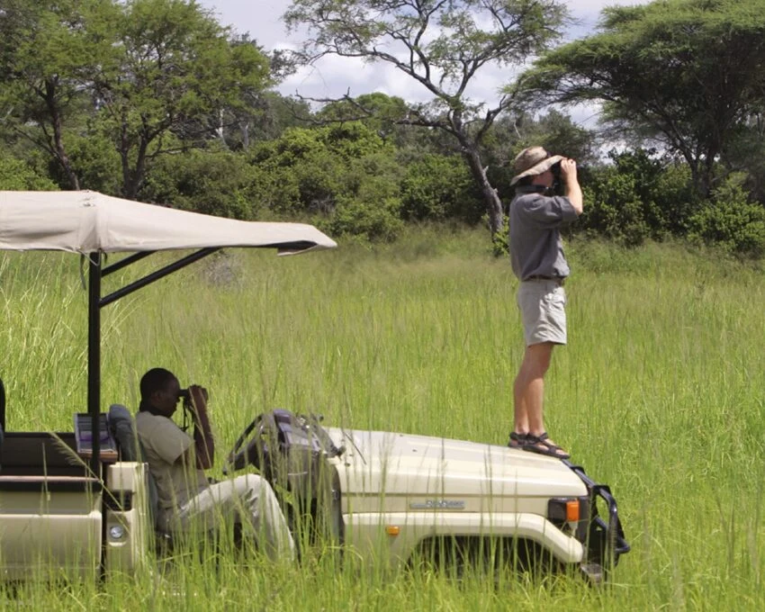 Guests with binoculars and cameras on an open safari vehicle in Katavi