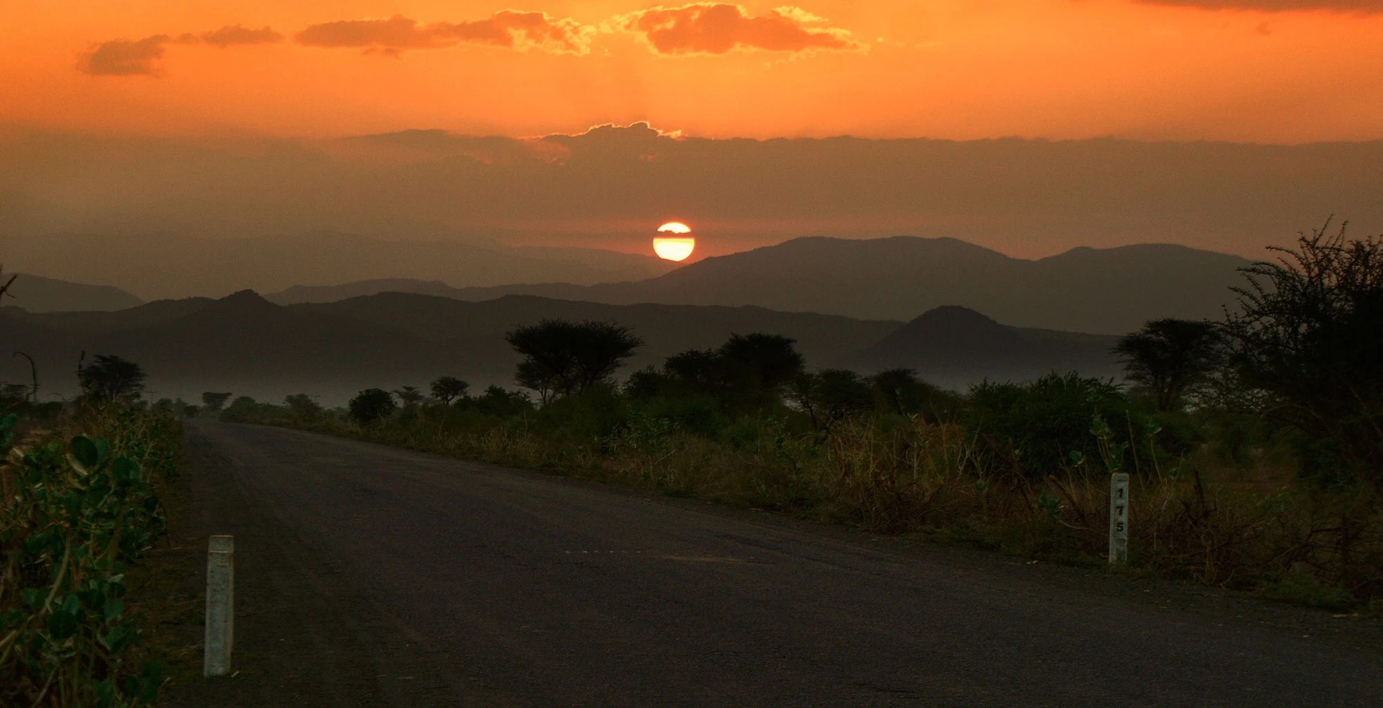Sun rising over hills beside a quiet road near Arba Minch
