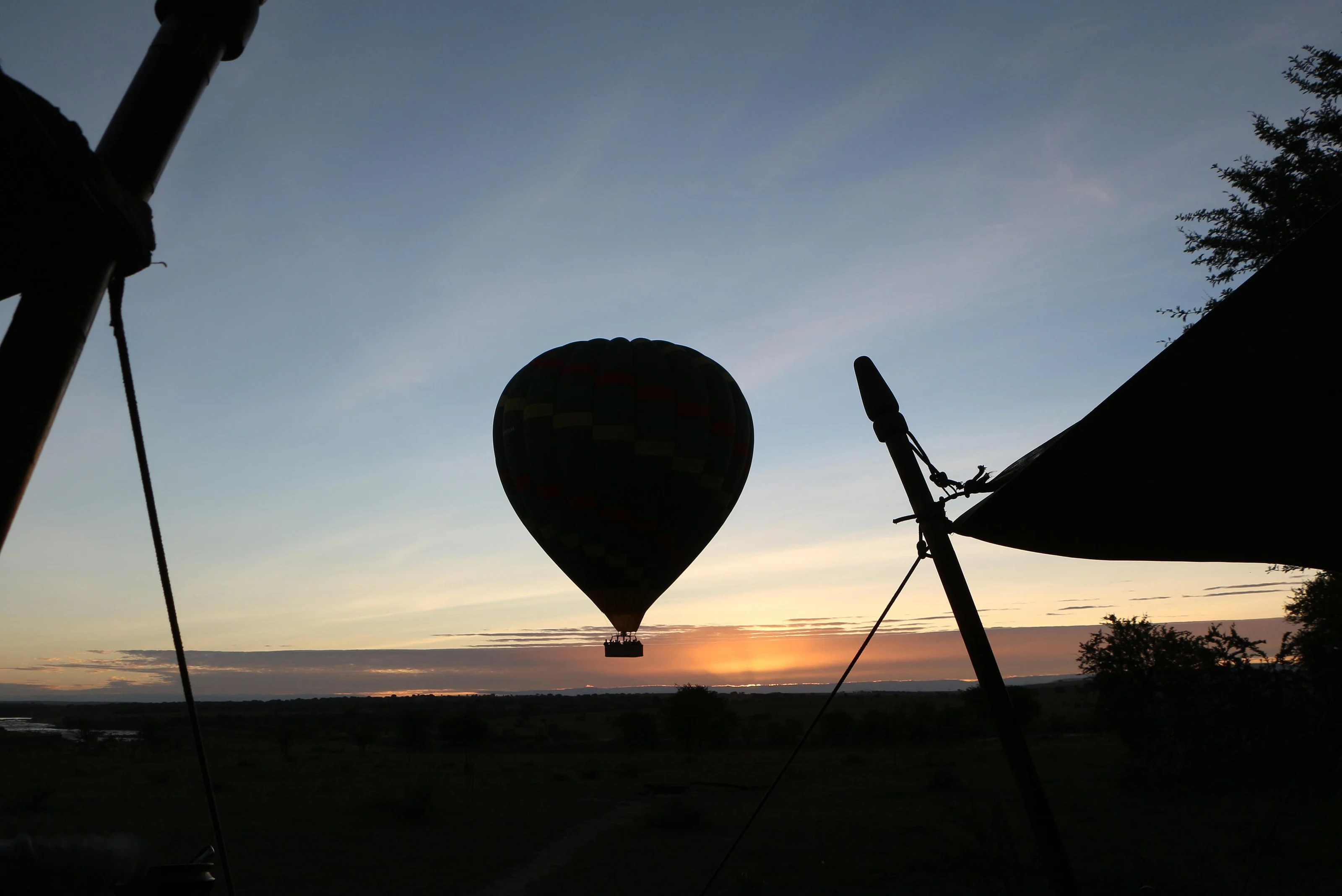 A hot-air balloon silhouetted at dawn seen from camp in the Serengeti