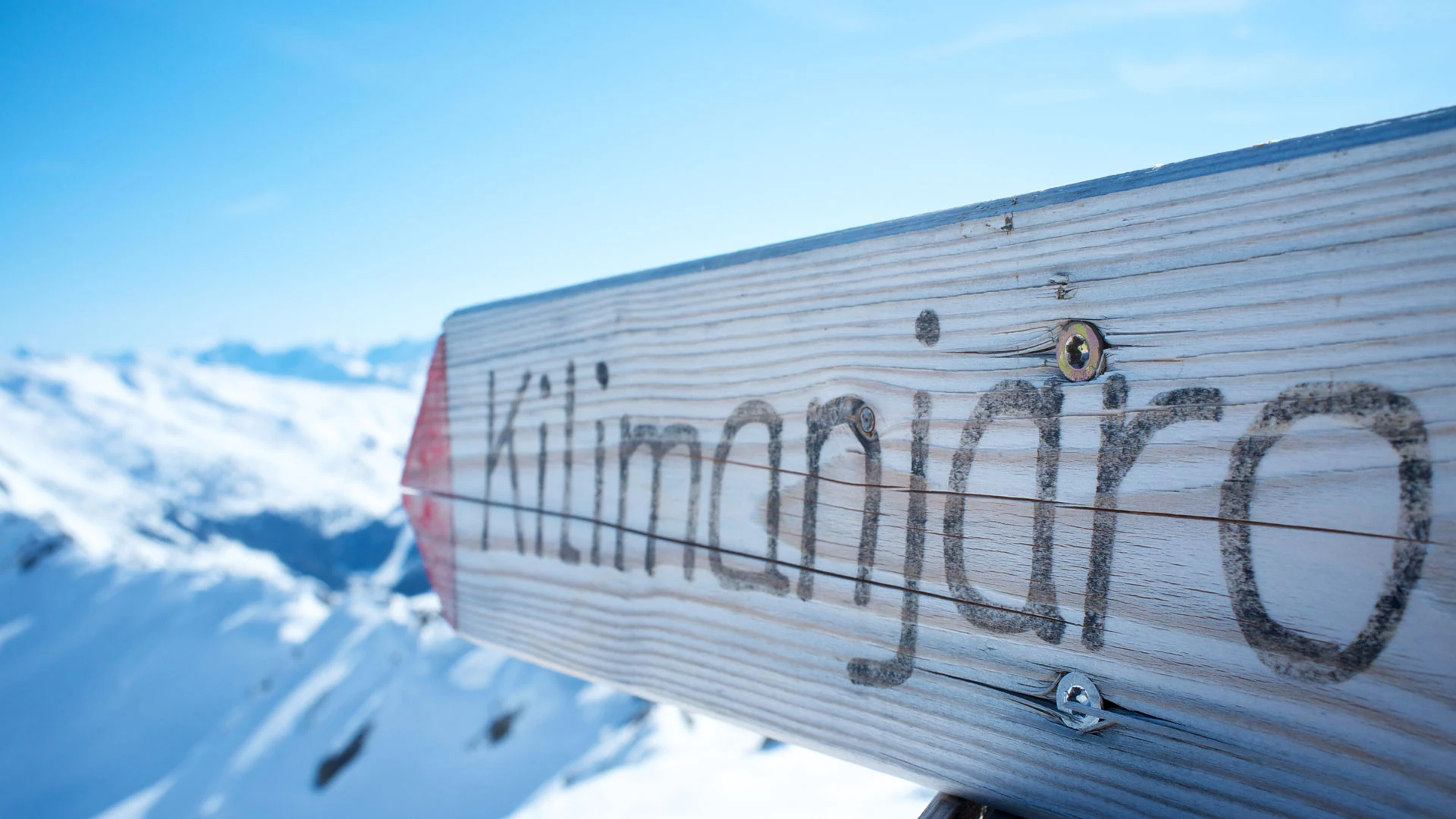Wooden Kilimanjaro signpost over snow with blue sky