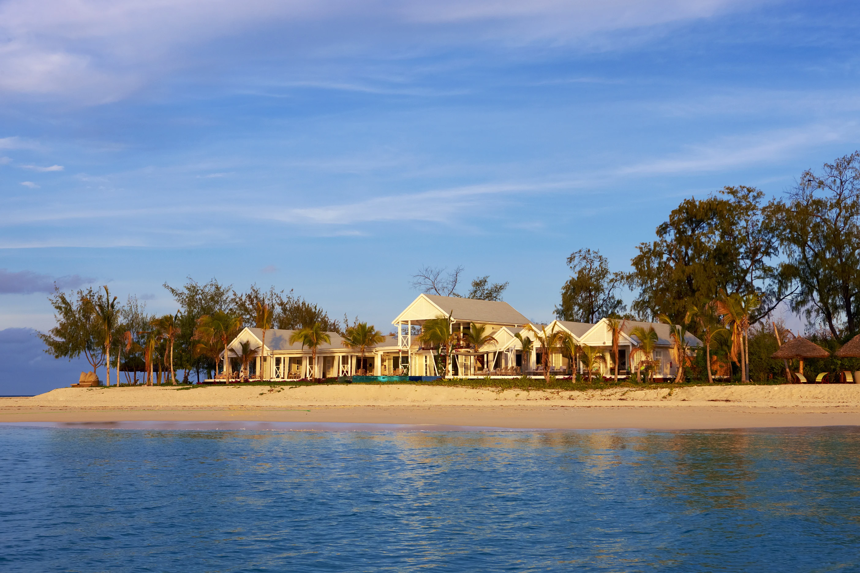 Beach villas behind a sandy shore and calm blue water