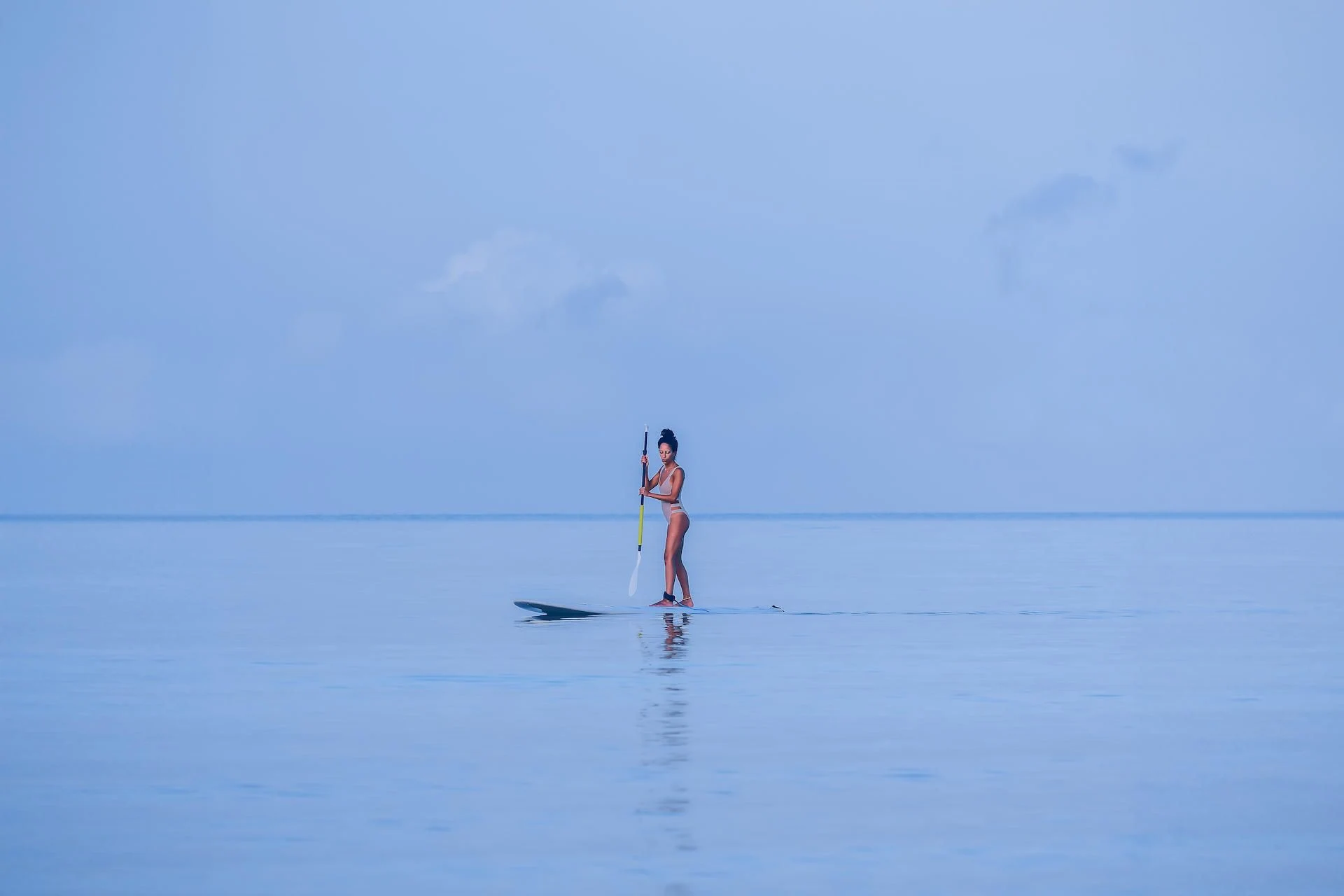 A distant paddleboarder over a shallow sand flat