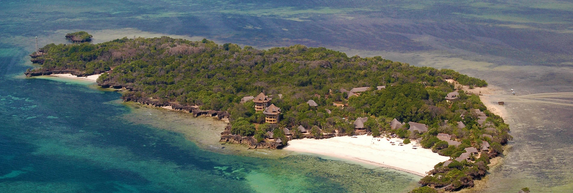 A forested island with a white beach and reef off Kenya's south coast, seen from the air