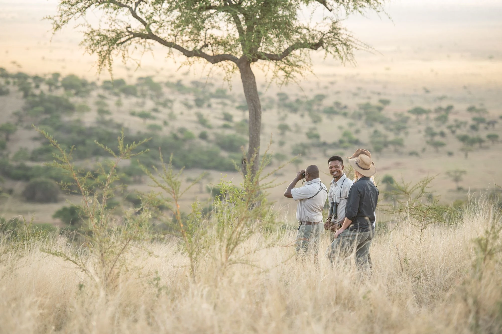 Guided walkers crossing open grassland in the Grumeti Reserve