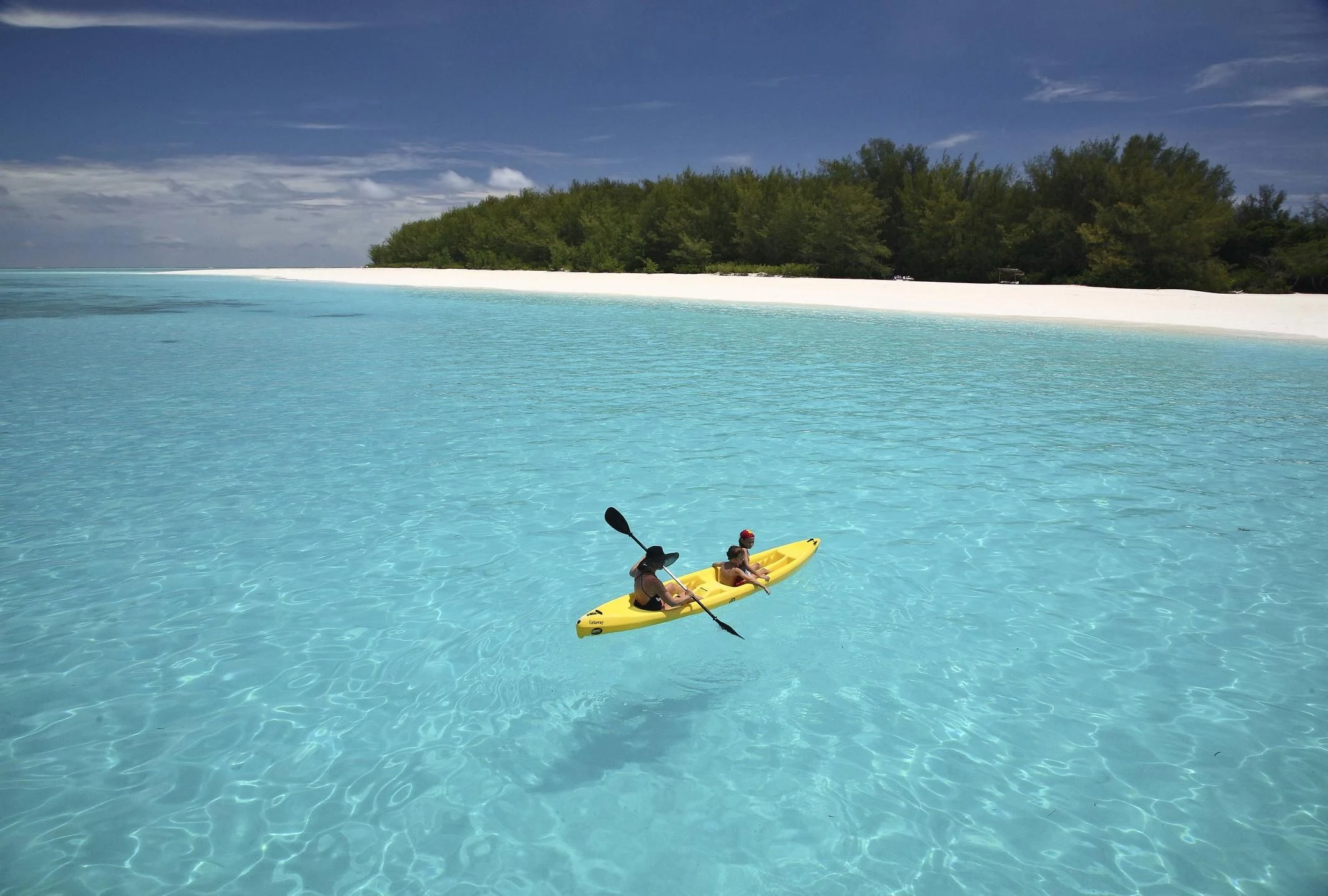 Kayaker in turquoise water with an island beach behind
