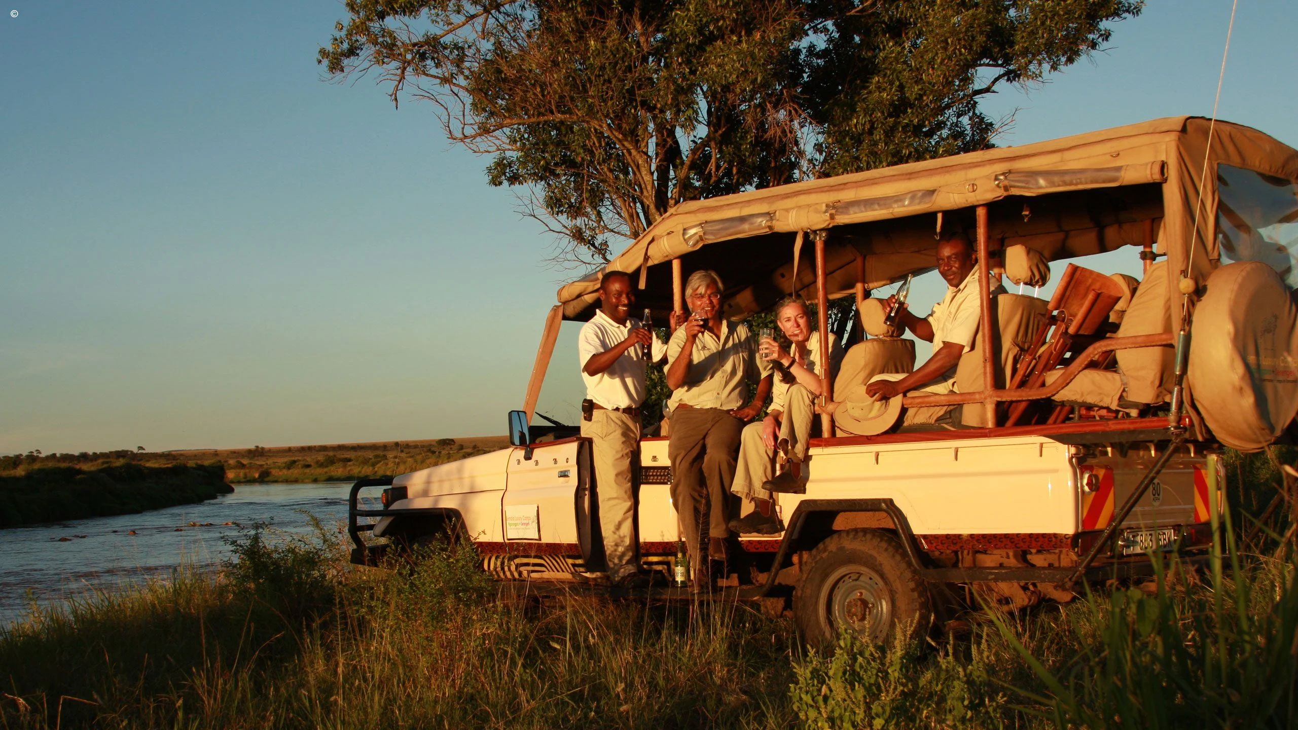 Visitors in a safari vehicle beside water in the Serengeti