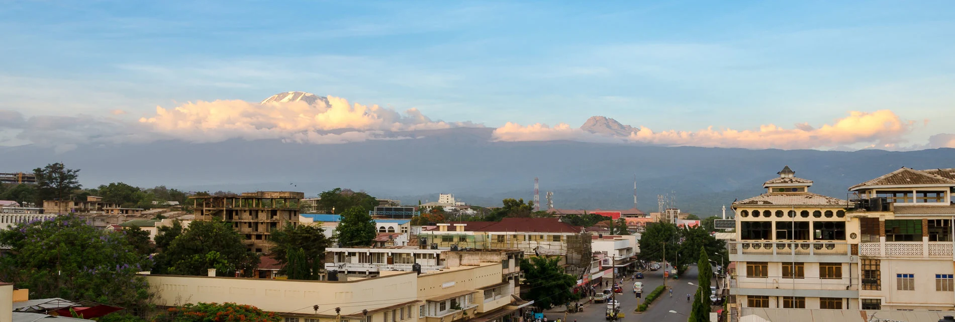 Moshi town rooftops with snow-capped Kilimanjaro rising behind the clouds