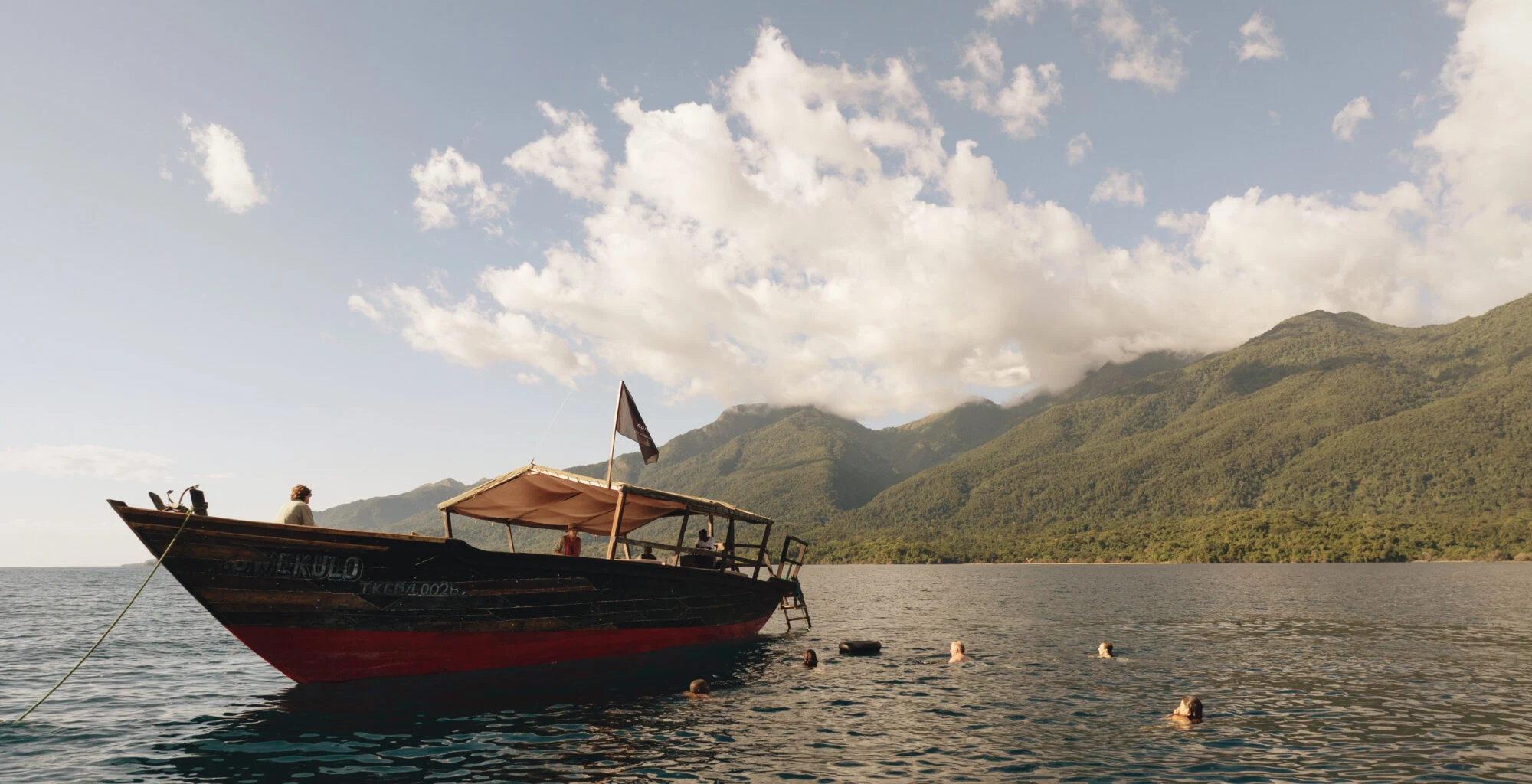 A wooden boat on Lake Tanganyika below the forested Mahale Mountains
