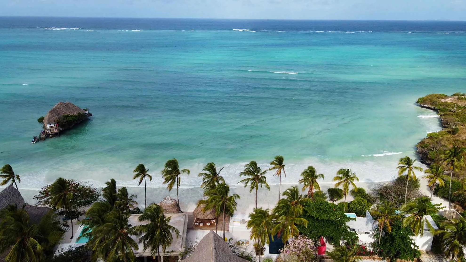 Palm trees and a sandy beach beside a shallow blue lagoon
