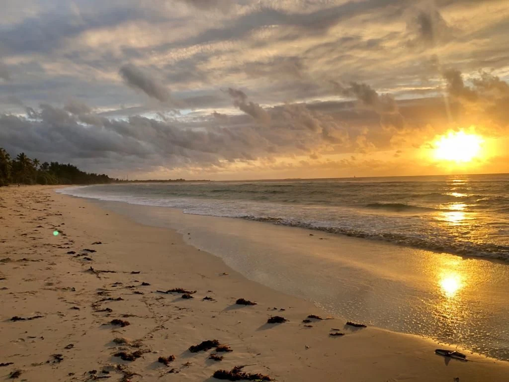 Sunrise over a quiet sandy beach with footprints