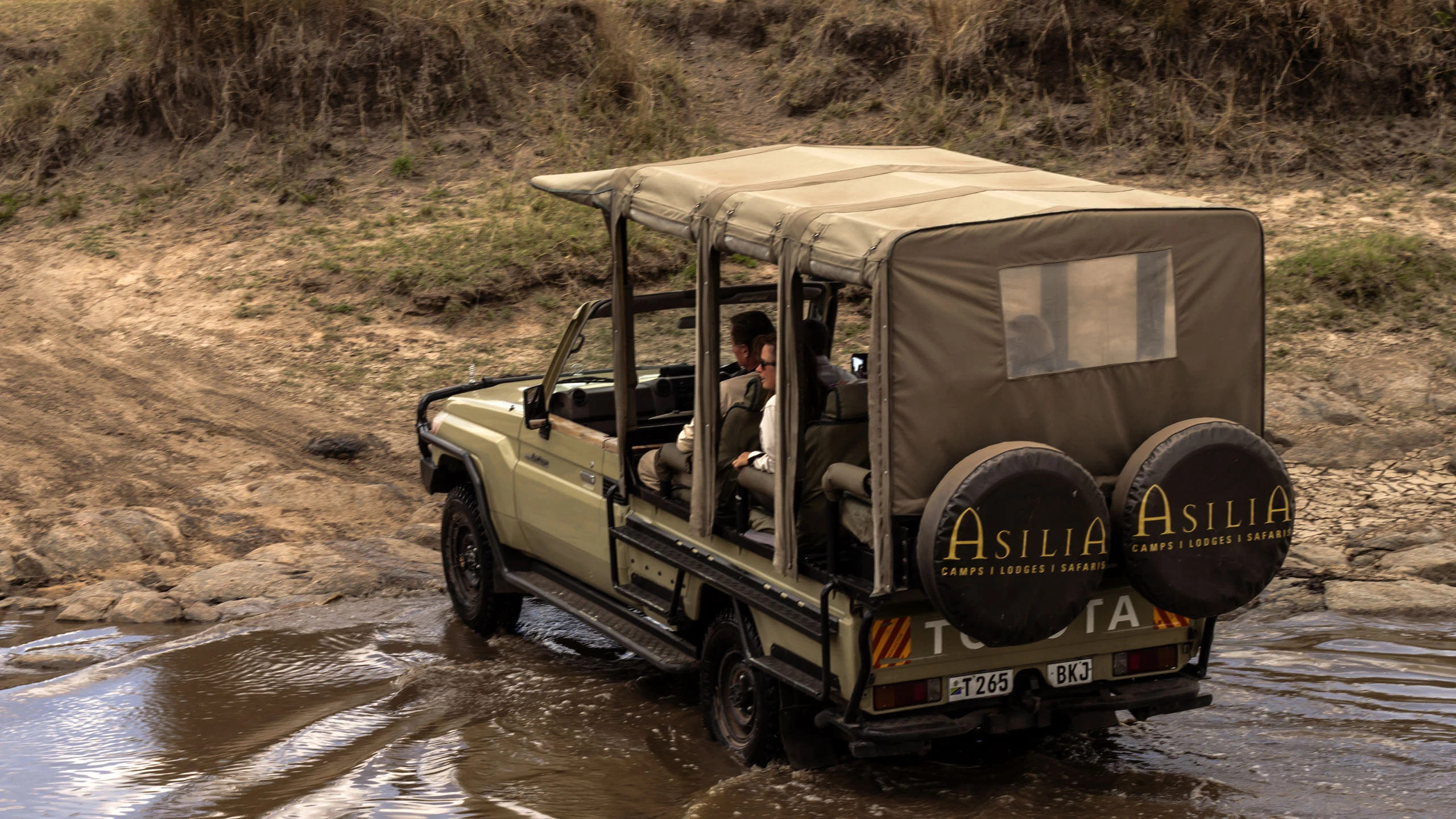 Safari vehicle crossing shallow river water in the Serengeti