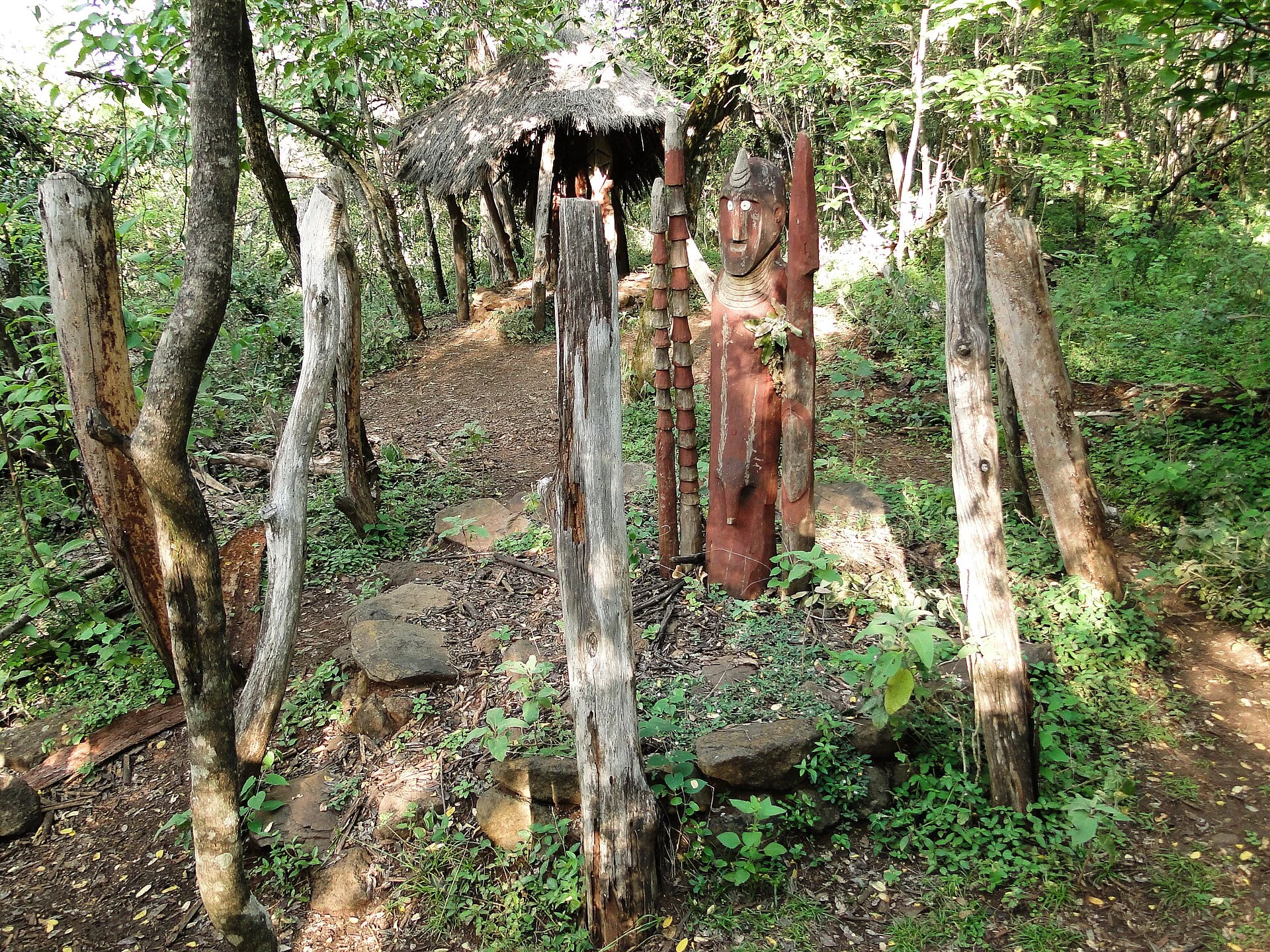 Carved wooden waga grave markers stand among trees in Konso.