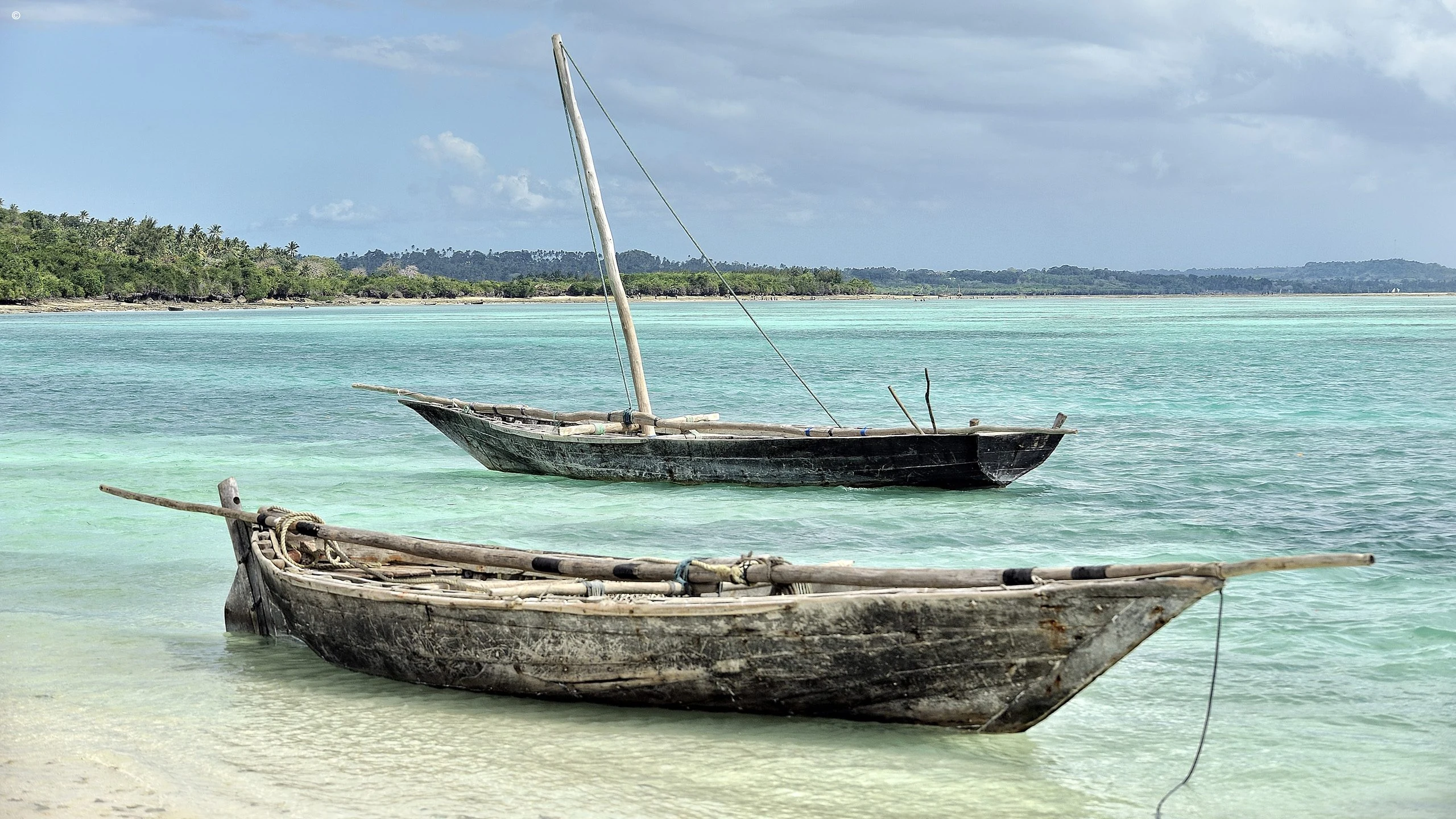 Two weathered wooden boats in shallow turquoise water