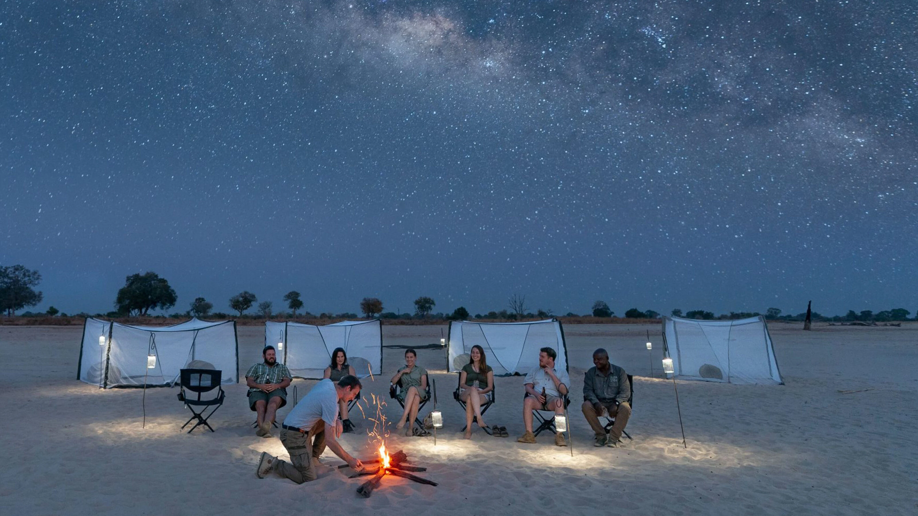 Guests around a campfire under the Milky Way